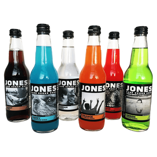 The Jones Soda 12 Pack by Vegas Party Favors includes six colorful bottles with unique flavors: Root Beer, Berry Lemonade, Cream Soda, Orange & Cream, Strawberry Lime, and Green Apple. Each carbonated delight features distinct labels.