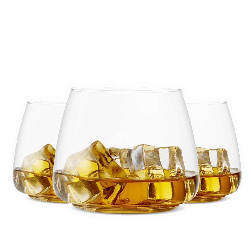 Three Vegas Party Favors BPA-free whiskey glasses, filled with amber whiskey and large ice cubes, are arranged in a triangle against a white background.